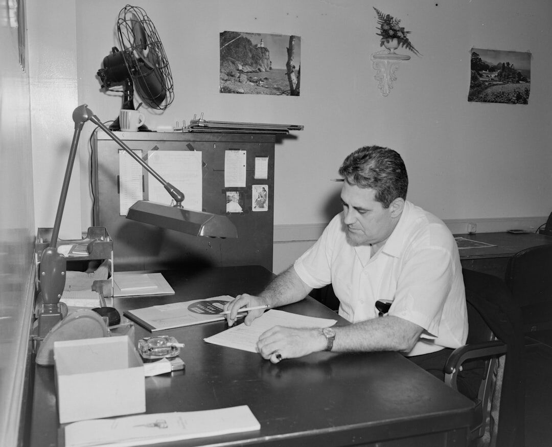 Photo editor working at a desk with contact sheets and a laptop